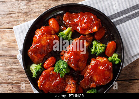 Cuisses de poulet au four avec sauce épicée catalina avec le brocoli et les tomates sur une plaque noire sur la table. Vue supérieure horizontale de abov Banque D'Images