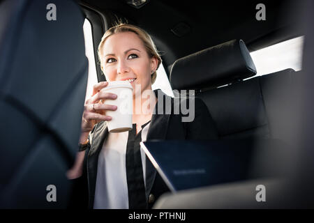 Smiling young businesswoman drinking café à emporter dans... Banque D'Images