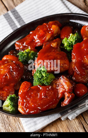 Des cuisses de poulet avec sauce Catalina avec brocoli et tomates sur une plaque verticale. Banque D'Images