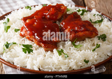 Poêlée de cuisses de poulet avec la sauce et garnir de riz catalina close-up sur une plaque horizontale sur la table. Banque D'Images