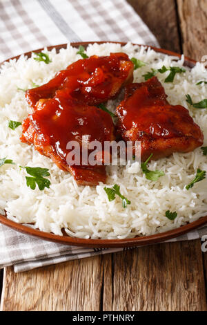 Cuisses de poulet frit avec sauce catalina servi avec du riz sur une plaque verticale sur la table. Banque D'Images