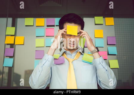 Portrait of young businessman préoccupé avec les adhésifs des notes sur son corps Banque D'Images