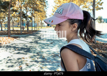 Petite fille avec chapeau rose et son sac à dos dans le parc Banque D'Images