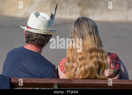 L'homme et la femme assis sur un banc en bois à l'été. Un homme portant un chapeau de Panama avec une plume dans son chapeau. Banque D'Images