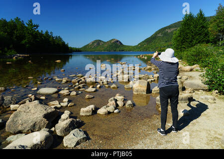 Femme de prendre une photo de l'étang de la Jordanie avec son téléphone portable.L'Acadia National Park, Maine, USA. Banque D'Images