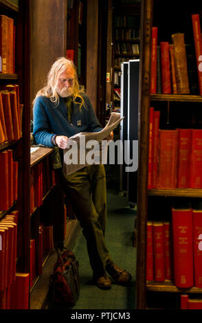 Man reading newspaper in bibliothèque. Banque D'Images