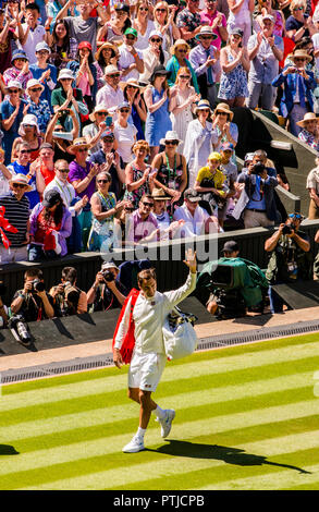 Roger Federer vagues à la foule dans la cour centrale après avoir remporté son premier match sur le premier jour de la Wimbledon. Banque D'Images