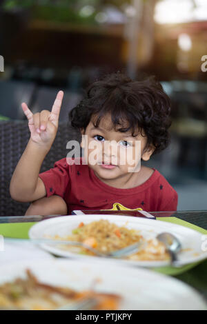 Image enfant asiatique cheveux bouclés concéder et manger le petit déjeuner dans un restaurant. Banque D'Images