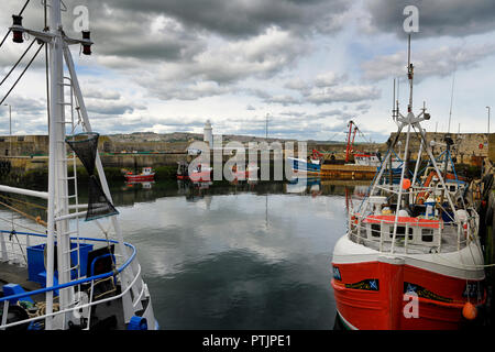 Le rouge et le bleu les bateaux de pêche et phare de MacDuff chantiers du port avec vue sur la baie de Banff Banff Aberdeenshire, Scotland UK Banque D'Images