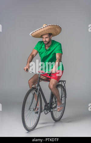Jeune homme barbu en sombrero mexicain équitation location sur gris Banque D'Images