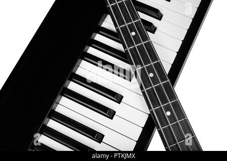 Le cou d'une guitare basse électrique 4 cordes portant sur les touches d'un piano isolé sur un fond blanc, pur Banque D'Images