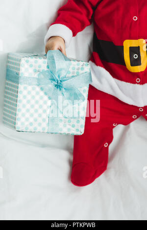 Cropped shot of little baby in santa suit couché dans crèche avec cadeaux de Noël Banque D'Images