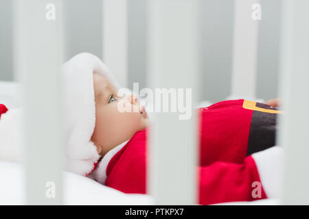 Close-up shot of cute little baby in santa suit lying in crib Banque D'Images