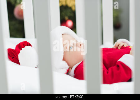 Gros plan d'adorables petits baby in santa suit lying in crib Banque D'Images