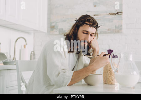 Jésus fatigué de manger des corn flakes au petit déjeuner dans la cuisine à la maison Banque D'Images