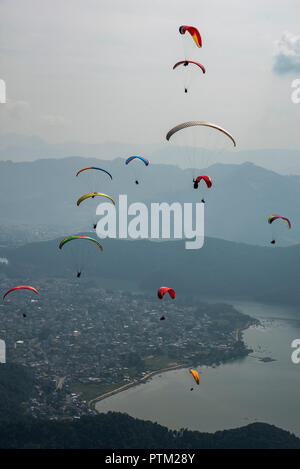 Parapentes planent au-dessus des collines de Pokhara au Népal. Banque D'Images