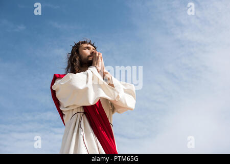 Low angle view of Jésus prier contre le ciel bleu Banque D'Images