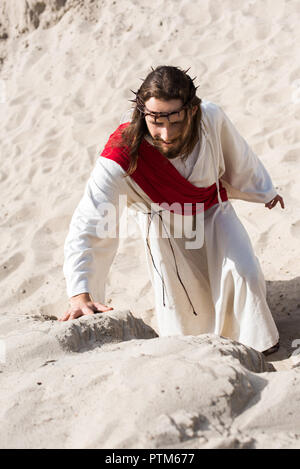 Portrait de Jésus en robe, ceinture rouge et couronne d'épines du désert de sable d'escalade Banque D'Images