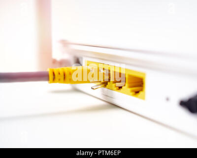 Close-up yellow câble Ethernet connecté sur internet sans fil blanc WIFI routeur concentrateur du réseau isolé sur fond blanc. Banque D'Images