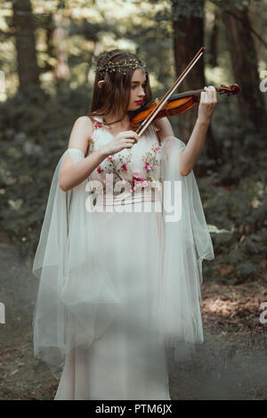 Belle elfe mystique à jouer du violon en forêt Banque D'Images