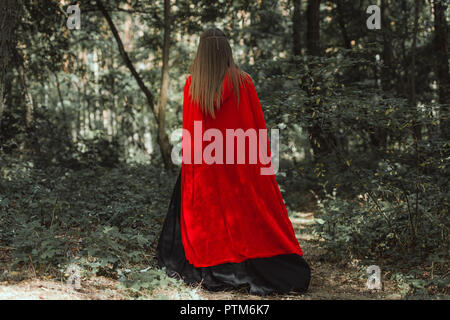 Vue arrière de mystic femme en manteau rouge en forêt Banque D'Images
