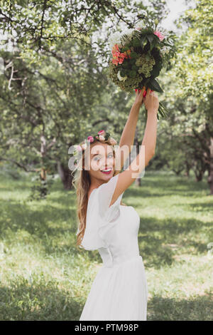 Beautiful smiling young bride pierres mariage bouquet in park Banque D'Images