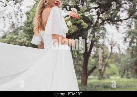 Cropped shot de jeune mariée robe de mariage en tenant un bouquet de fleurs à l'extérieur Banque D'Images