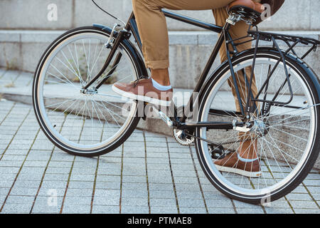 Cropped shot of man riding bicycle on street