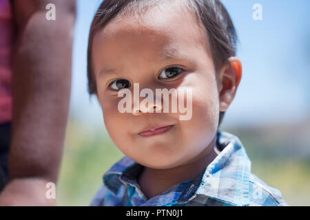 Smart 2 ans garçon avec des yeux brillants et sourire mignon et innocent à debout à côté de sœur dans un parc extérieur en été Banque D'Images