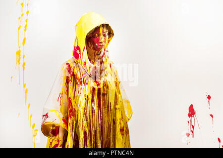 Belle femme en imperméable peint avec les peintures jaune et rouge aux yeux clos permanent isolated on white Banque D'Images