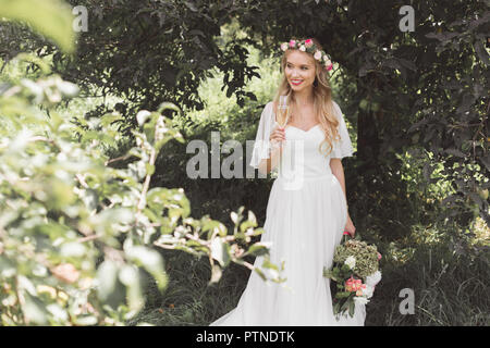 Beautiful smiling young bride holding bouquet de mariage et d'un verre de vin dans la région de park Banque D'Images