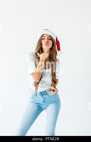 Jolie jeune fille à santa hat blowing kiss, isolated on white Banque D'Images