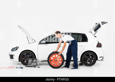 Vue latérale du mécanicien auto pneu poussant au changement ancien sur white Banque D'Images