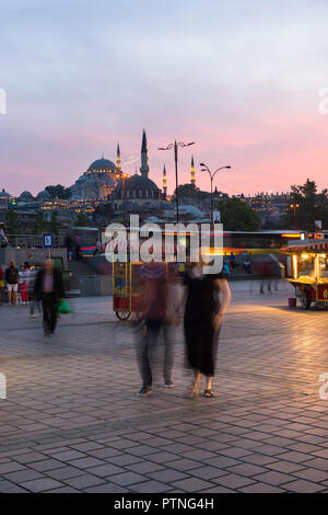 Bazar d'Eminonu avec des stands de nourriture et les gens avec la mosquée Suleymaniye allume à l'arrière-plan au coucher du soleil, Istanbul, Turquie Banque D'Images