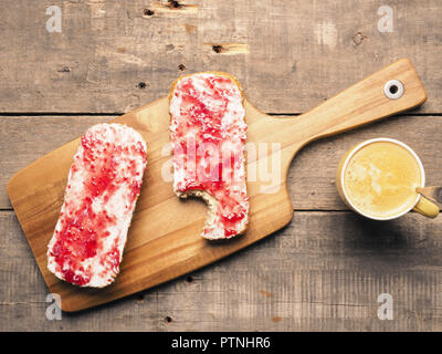 Grains entiers biologiques sains bobines avec sweet et savoureux Confiture de framboises sur une planche à découper en bois Banque D'Images