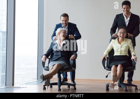 Heureux divers employés de rire équitation sur des chaises dans office Banque D'Images
