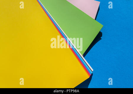 Feuilles de documents dynamiques colorés sur fond bleu Vue de dessus - palette de couleurs Banque D'Images
