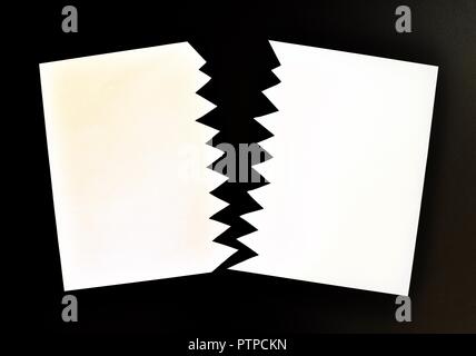 Concept de divisé ou séparé en deux feuilles de papier déchiré. Papier blanc déchiré dans la moitié isolé sur fond noir. Vue d'en haut Banque D'Images