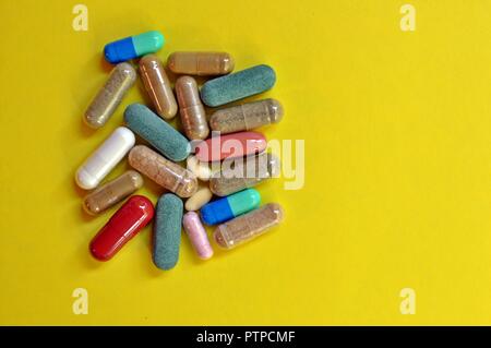 Comprimés colorés sur fond jaune. Comprimés et gélules avec copie espace. Vue de dessus de capsules. Différents types de médicaments Banque D'Images