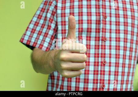 Concept d'un doigt vers le haut sens OK, faite par un homme part avec focus sélectif et close up on rouge à carreaux et une chemise blanche background Banque D'Images