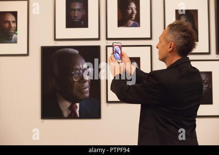 Les visiteurs de la 'Black est le nouveau noir' exposition de portraits par photographe Simon Frederick à la National Portrait Gallery peut utiliser une application pour la li Banque D'Images