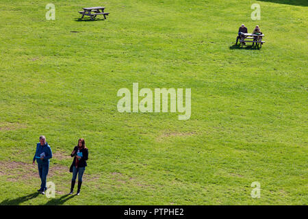 Deux couples dans le parc de Ludlow castle, l'un explorant l'autre couple s'asseoir à un banc à l'automne, soleil, Ludlow, Shropshire, Angleterre Banque D'Images