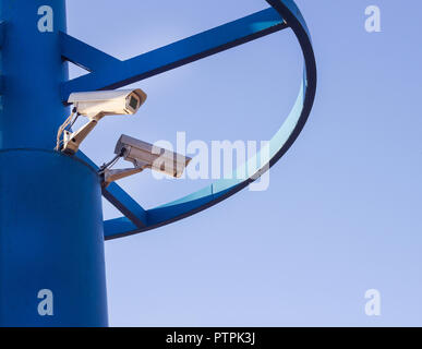 Deux caméras de surveillance sur un pilier bleu contre un fond de ciel bleu Banque D'Images
