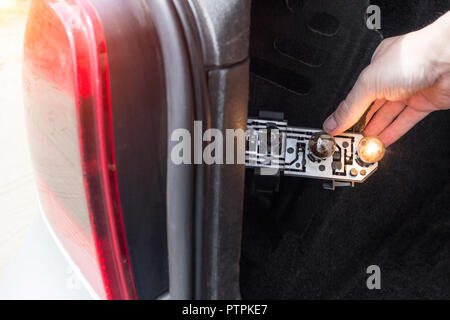 Un homme est en train de changer une ampoule dans l'arrière de la voiture, close-up Banque D'Images