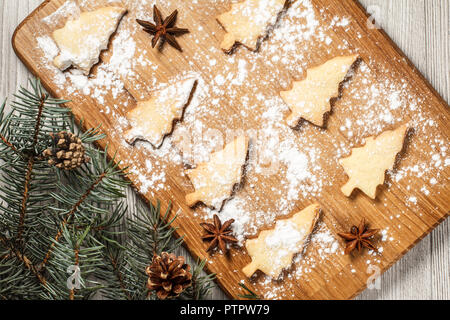Gingerbread cookies en forme d'arbre de Noël sur planche de bois saupoudré de sucre en poudre avec l'anis étoilé et les branches de sapins naturels avec les cônes. À Banque D'Images