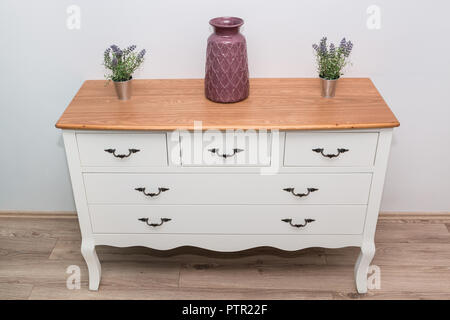 Commode en bois blanc avec trois vases et fleurs sur le mur blanc arrière-plan. Commode close up. Banque D'Images