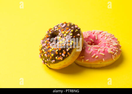 Rose et chocolat donuts se trouvent sur un fond jaune. copy space Banque D'Images