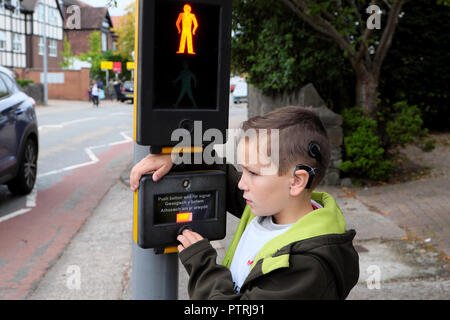 Un jeune garçon 8 à l'école à pied en attendant de traverser la route à un passage à niveau piéton des feux de circulation dans une zone urbaine UK KATHY DEWITT Banque D'Images