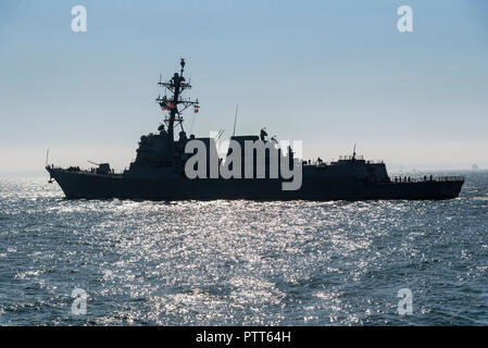 Le port de Portsmouth, Royaume-Uni. 10 octobre, 2018. Le navire de guerre américain USS Farragut une silhouette sur le soleil faible au départ de Portsmouth, Angleterre, Royaume-Uni Banque D'Images