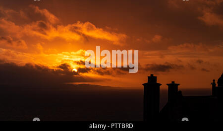 Lyme Regis, dans le Dorset, UK. 11 octobre 2018. Météo France : toits dans le quartier historique de la ville de Lyme Regis sont silhouetté contre moody ciel comme les nuages de tempête orange glow au lever du soleil sur ce qui est défini pour être un jour pluvieux et venteux à Lyme Regis. Credit : PQ/Alamy Live News Banque D'Images